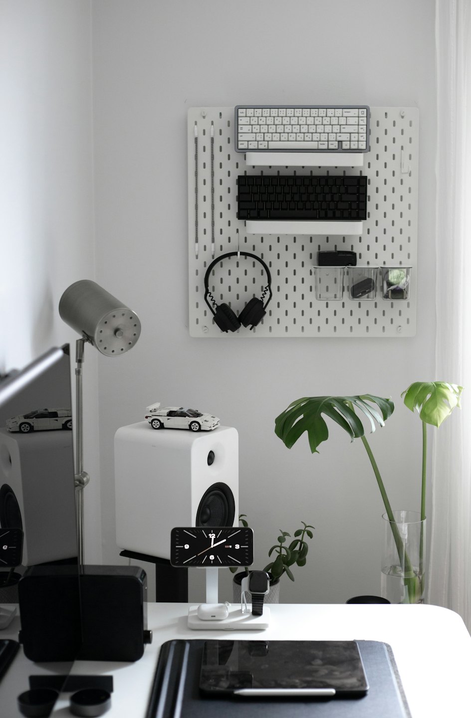 Modern minimalist desk with tech gadgets and Monstera plant.