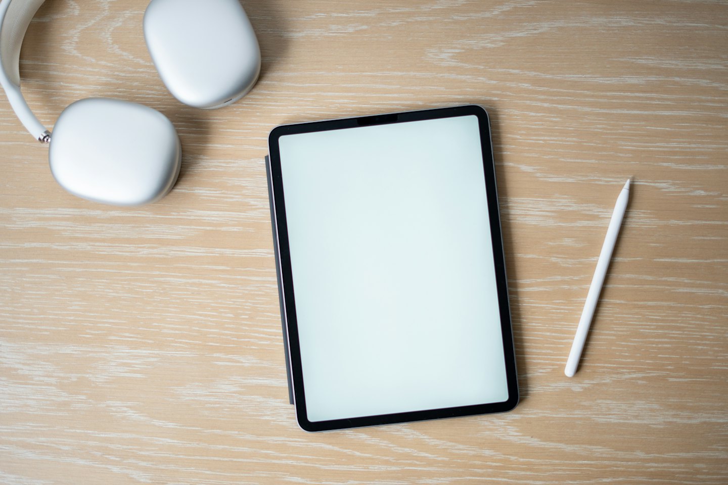 Modern tablet with headphones and stylus on a wooden desk.
