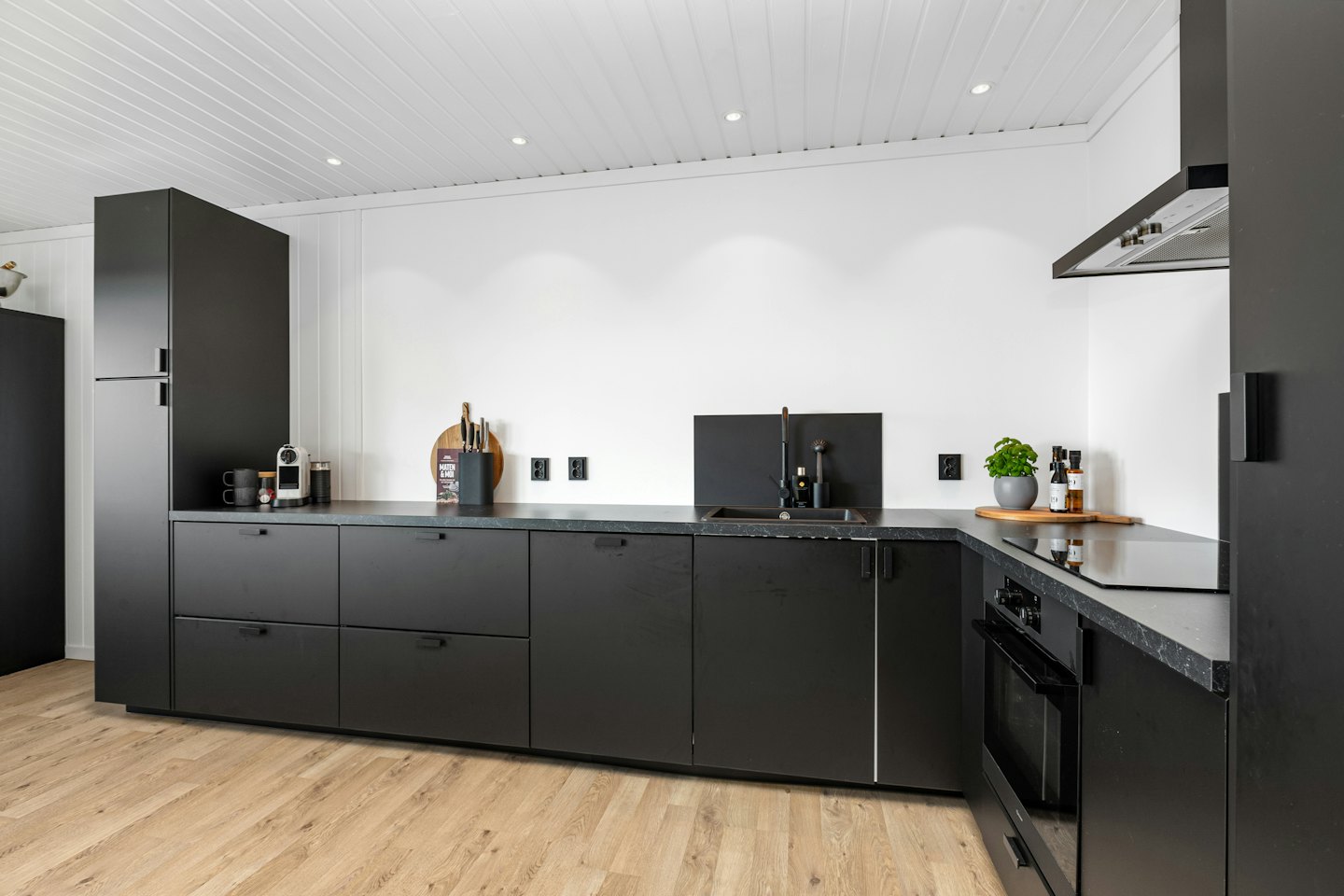 Modern kitchen with black cabinets and wooden floors.