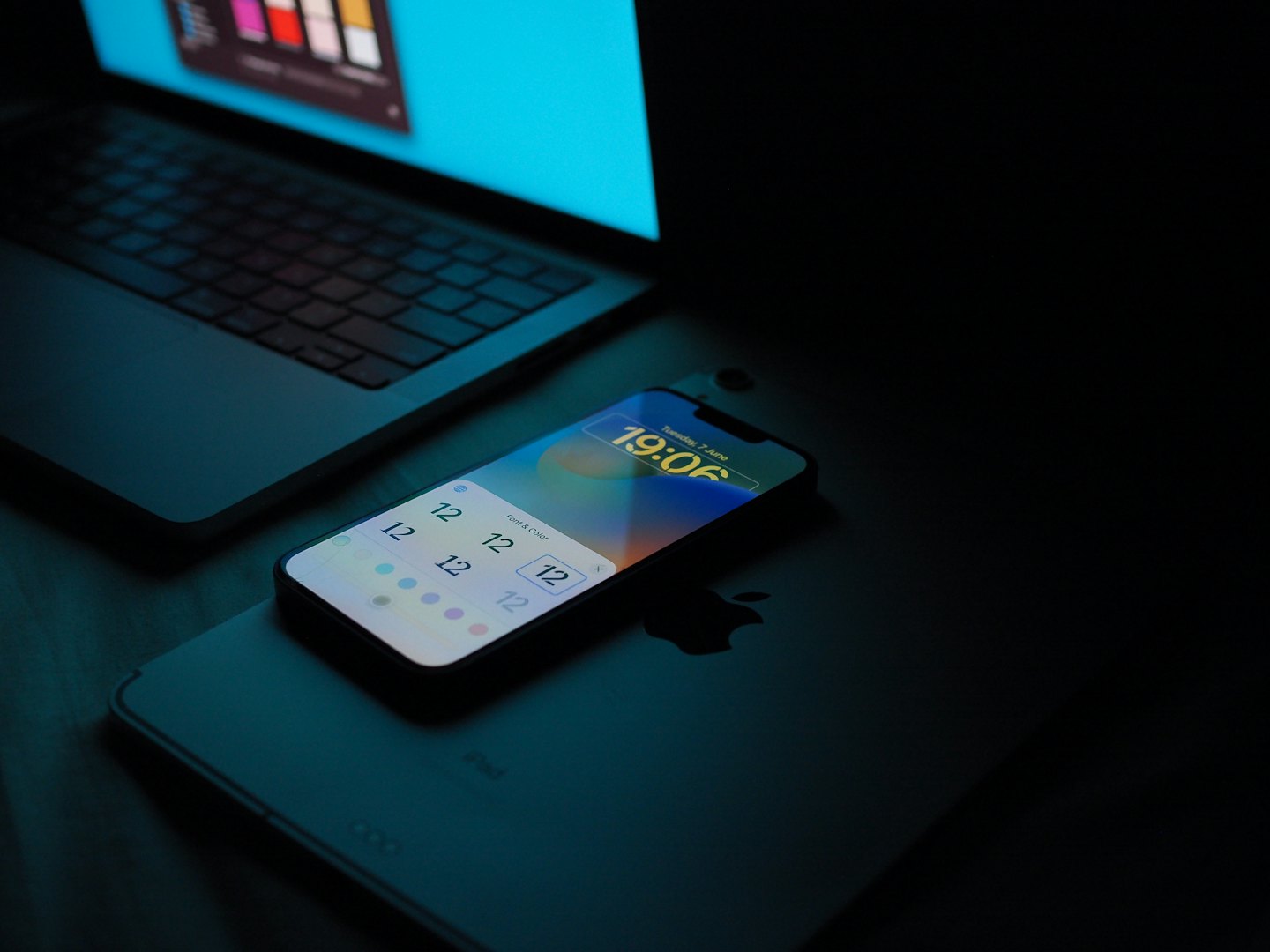 A smartphone resting on a tablet with an open laptop.